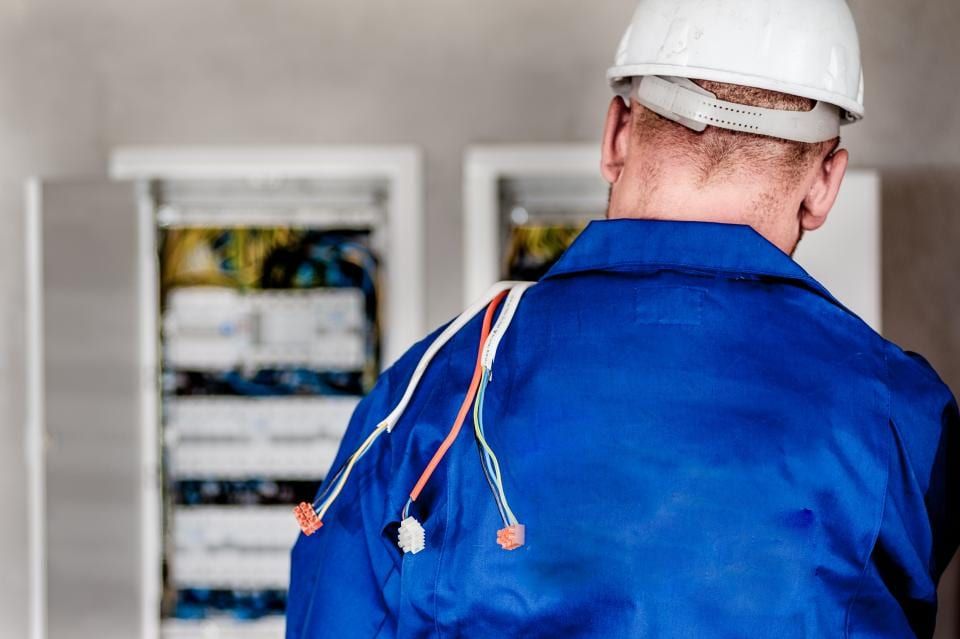An electrician working at an open breaker panel